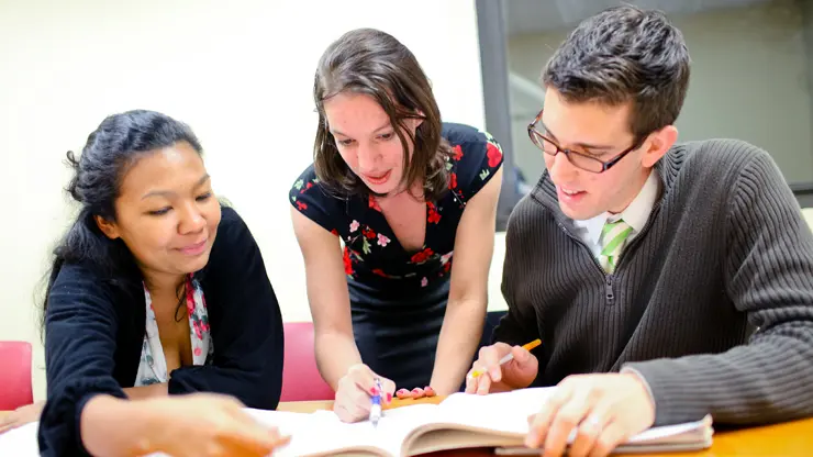 Executive English students working together on course materials during a small group business English class.