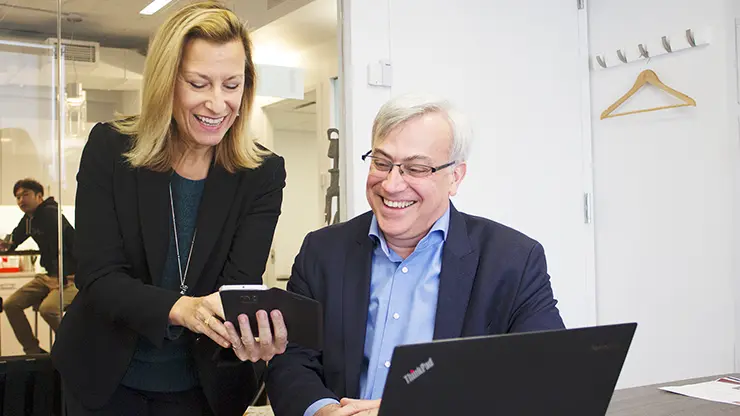 Executive English student receiving one-on-one instruction while working on a laptop in a professional office setting.