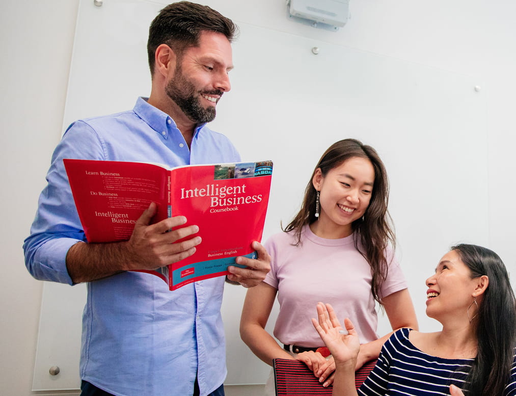 Rennert classroom with a teacher holding an 'Intelligent Business' coursebook