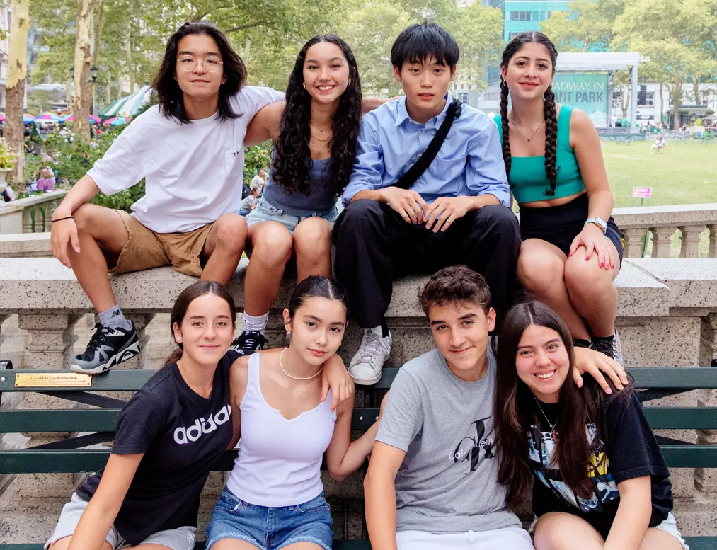 Teens in the Rennert New York English program sitting outdoors in Bryant Park, enjoying their time.